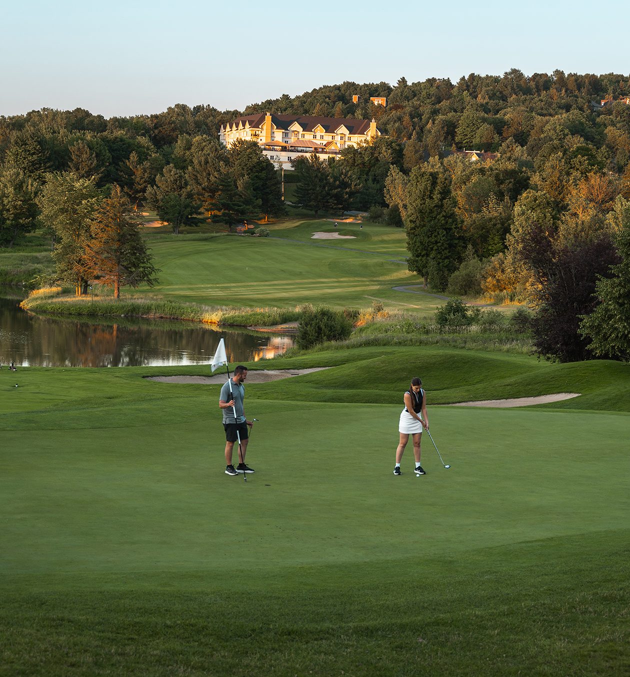 2 joueurs au golf Château-Bromont avec l'hôtel et les condos Château-Bromont en arrière-plan