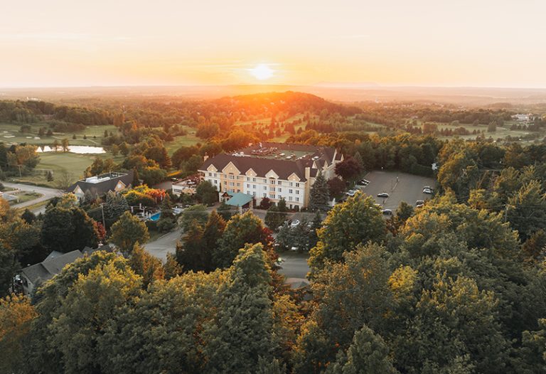 Vue extérieure du Château-Bromont entouré de verdure au lever du soleil