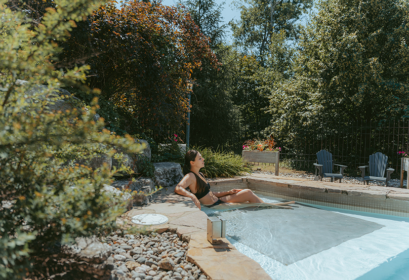 Personne se relaxant dans un bassin extérieur entouré de verdure au Château-Bromont